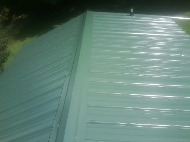 New green metal panels meeting at the ridge of a roof — Flat Roof Repair work by our crew in Valleyford