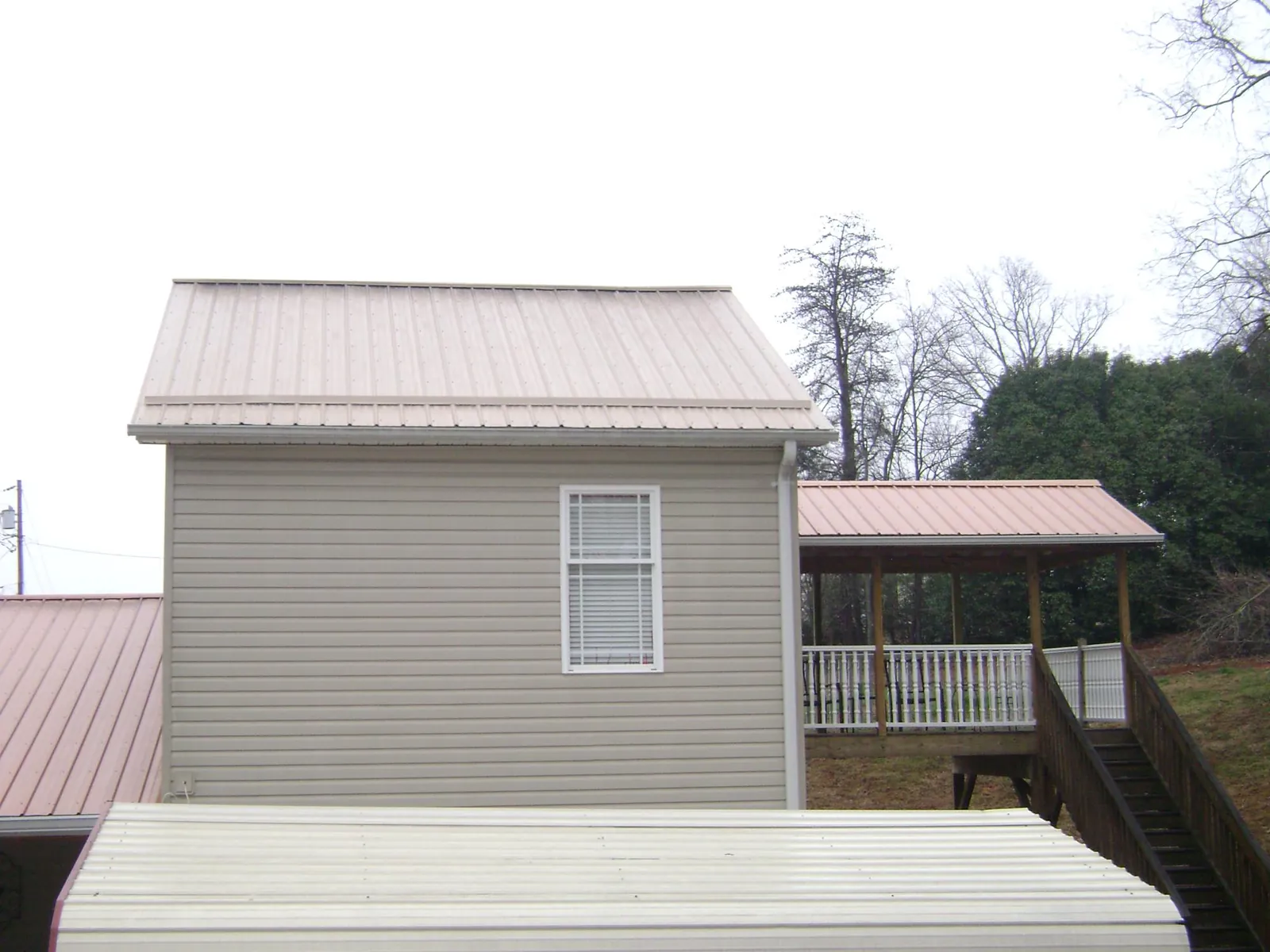 Tan metal roofs on a two story addition and attached porch, from a Roof Replacement job in Valleyford